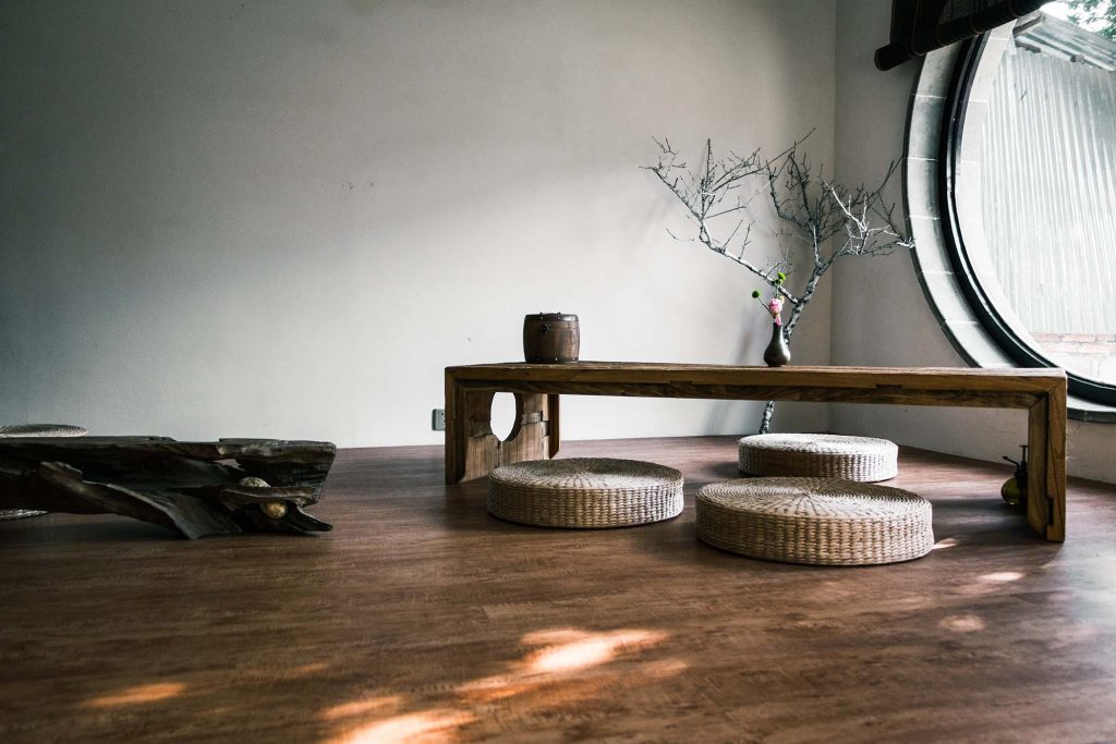 Espacio interior de estilo japonés con mesa baja de madera y asientos de fibras naturales