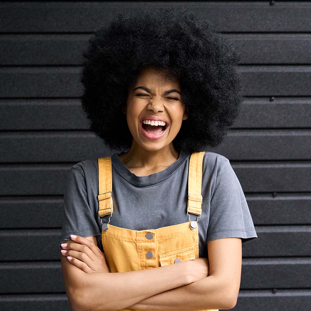 Persona joven sonriendo con expresión alegre frente a una pared moderna