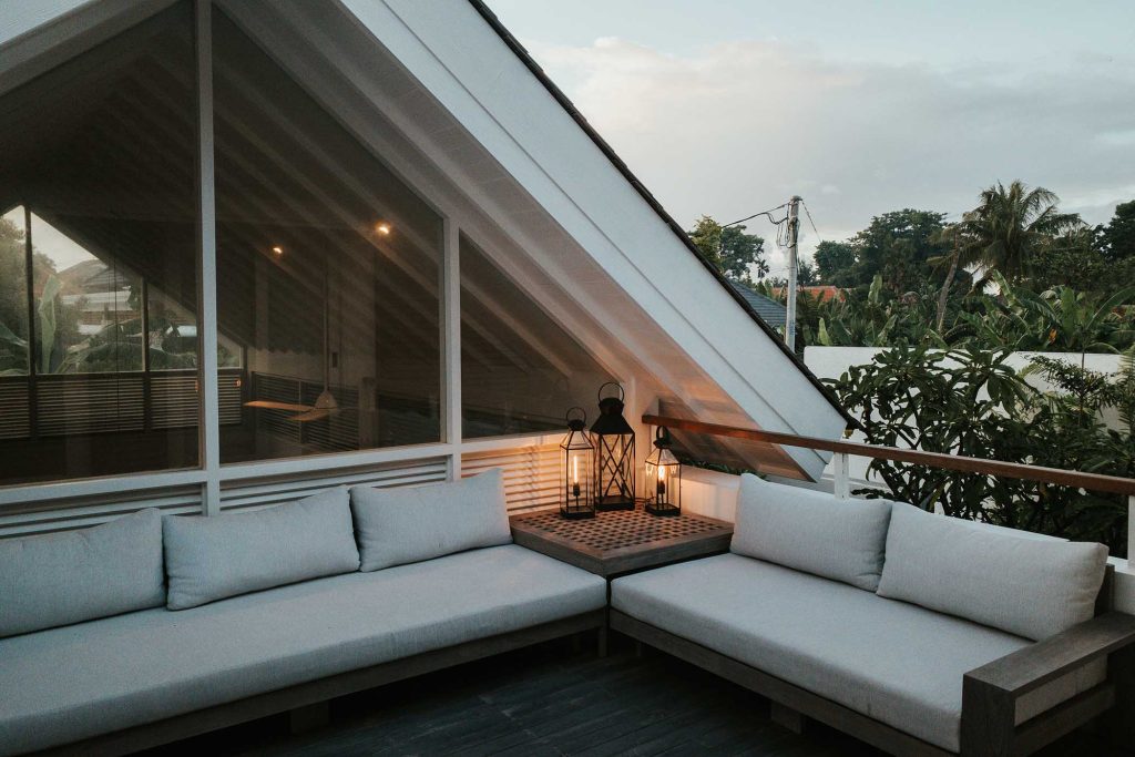 Terraza moderna con sofás en L e iluminación cálida con faroles decorativos
